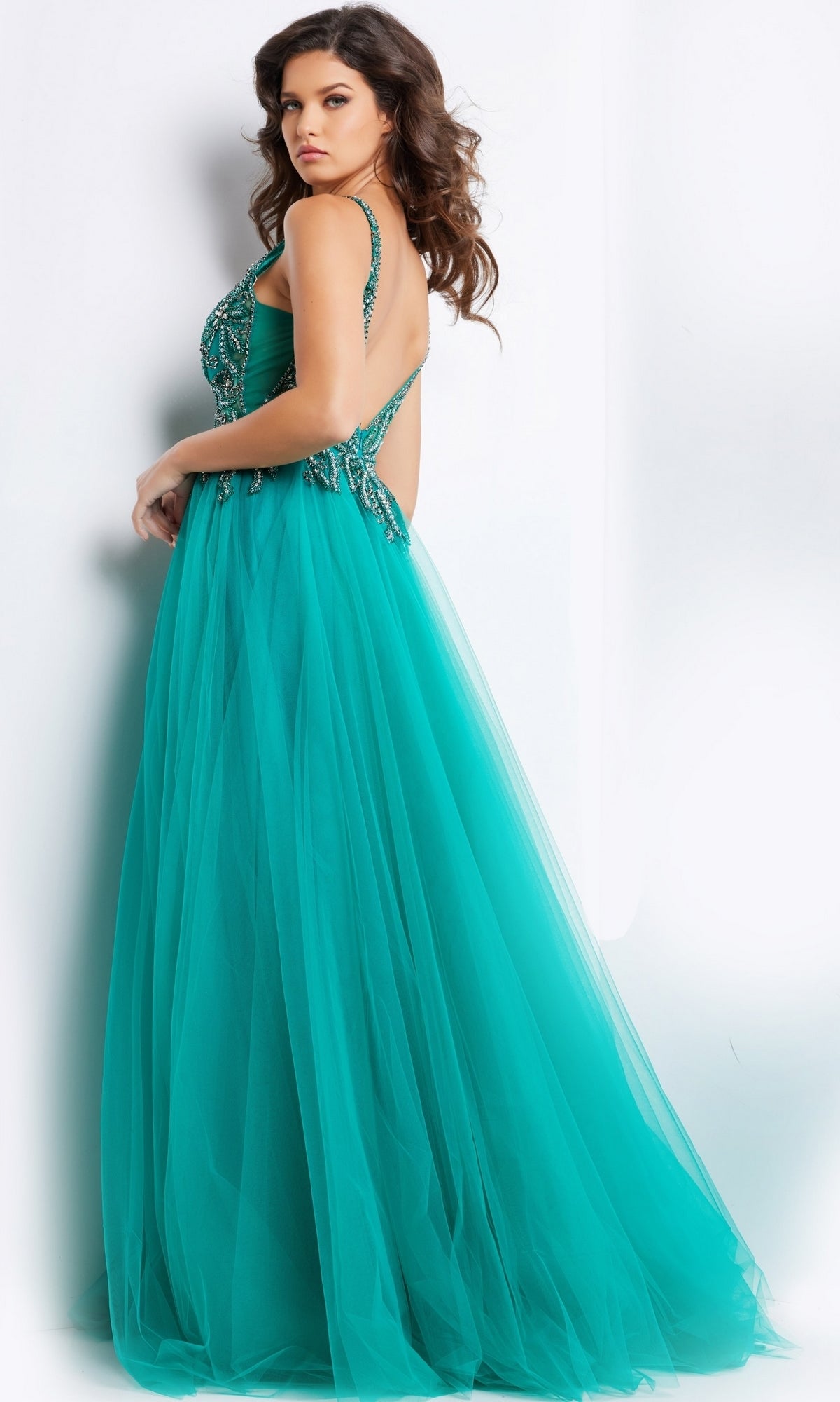 A woman models the Jovani Beaded-Bodice Long Prom Ball Gown 23962 in teal, featuring a beaded bodice and open back, standing against a plain white background.